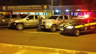 As duas caminhonetes apreendidas ontem à noite e um dos detidos, em frente à delegacia da PRF em Dourados (Foto: Divulgação)