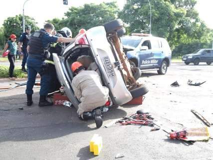Carro fura semáforo em avenida, bate em viatura da Polícia Militar e tomba