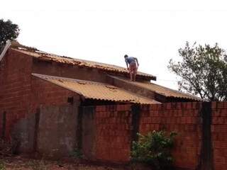 Morador tentando consertar estrago que tempestade provocou em telhado de residência (Foto: Rio Pardo News) 