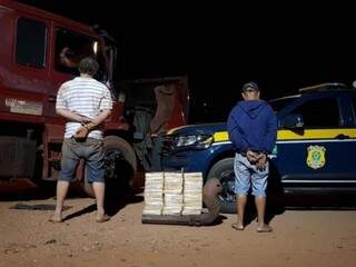 Dupla ao lado dos tabletes de cocaína que traficavam. (Foto: Divulgação/PRF) 
