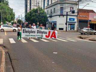 Manifestantes seguram faixa pedindo eleições diretas em ato no centro de Campo Grande, nesta manhã (21). (Foto: Amanda Bogo)