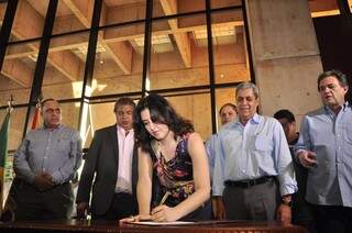Simone assinado o termo de posse como secretária, sob olha de André e Moka (Foto: João Garrigó)