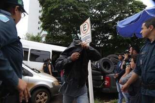 Policial preso cobre o rosto ao chegar preso à Corregedoria da PM.  (Foto: Fernando Antunes)