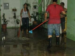 Depois da chuva,  Katiucy tira a água que invadiu a casa dela. (Foto: Alcides Neto) 