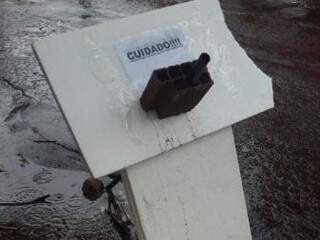 Moradores improvisaram placa para sinalizar o buraco.  (Foto: Direto das ruas) 