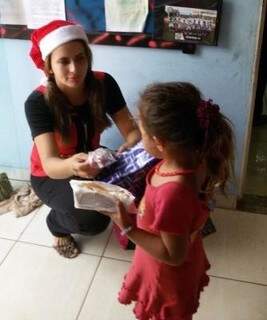 Voluntária entrega presentes para criança. 