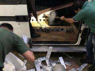 Agentes da PF retiram tabletes de maconha do fundo falso da van (Foto: Divulgação)