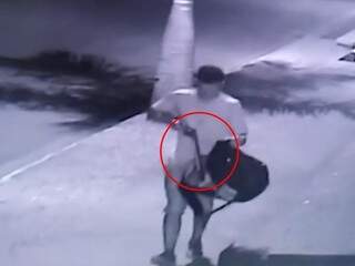 Em imagem de câmera de segurança, homem aparece tirando arma de cano longo da mochila (Foto: Reprodução)