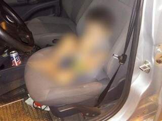 Criança no banco de carro depois de ser encontrada sozinha. A imagem dele está borrada em cumprimento ao ECA. (Foto: Divulgação PM).