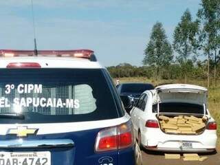 Viatura da PM de Coronel Sapucaia perto de veículo carregado com maconha (Foto: Assessoria/ PM)
