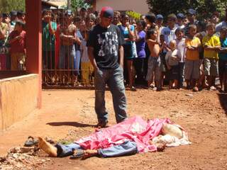 Irmão observa corpo de adolescente assassinado (Foto:Osvaldo Duarte/site Dourados News)
