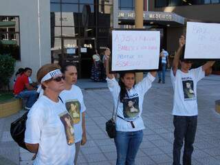 Sem poder entrar em sala de audiência, familiares de Brunão seguram cartazes de protesto em frente ao Fórum. (Foto: Simão Nogueira)