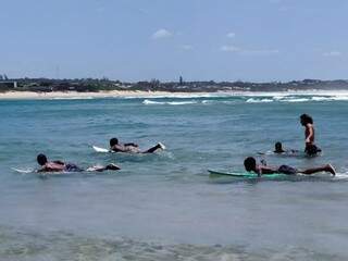 Os alunos aprendendo a surfar no mar com a ajuda do professor Gabriel Carrião. (Foto: Arquivo Pessoal)