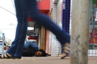 Homem dorme na calçada de uma farmácia da 14 de julho (Foto: André Bittar)