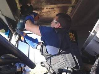 Policial usa máquina de cortar ferro para retirar tabletes escondidos em compartimento de carreta. O flagrante foi no Km 9 da BR-487, na cidade de Alto Paraíso (PR). (Foto: Divulgação/PRF)
