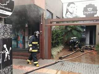 Bombeiros em loja e salão que pegaram fogo nesta terça-feira em Dourados (Foto: Adilson Domingos)