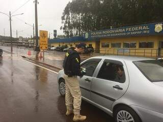 Mesmo com chuva, policiais rodoviários vistoriam veículos na BR-163, em Dourados, no 1º dia da operação (Foto: Divulgação)