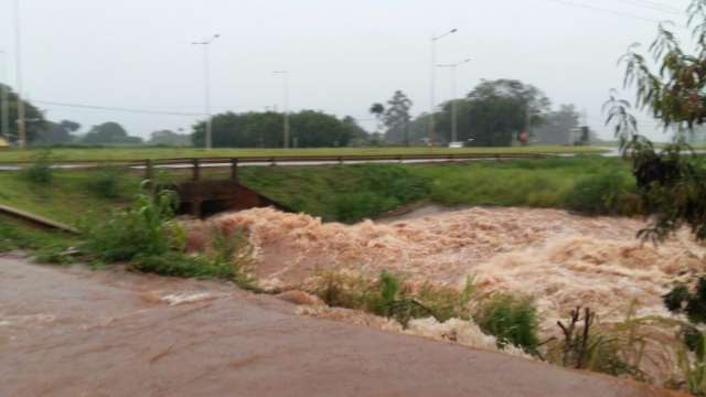 Chuva forte e r&aacute;pida alaga ruas e faz c&oacute;rrego transbordar no interior