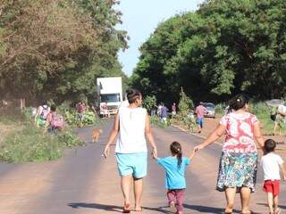 Família anda no meio da rodovia, bloqueada por moradores para protesto. (Foto: Henrique Kawaminami).