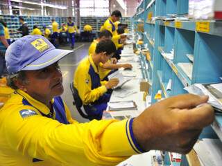 Funcionários dos Correios separando correspondências para entrega (Foto: João Garrigó)