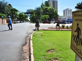 Faixa indicada na placa faz falta para que Cláudia e a mãe, ao fundo, atravessem a avenida. (Foto: João Garrigó)