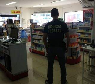 Agente da PF cumpre mandado em uma farmácia em Caarapó (Foto: Divulgação)