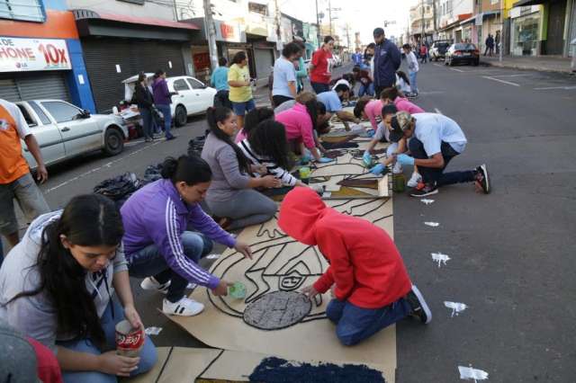 Ap&oacute;s noite chuvosa, fi&eacute;is madrugam para colorir 1 km de rua em dia santo 