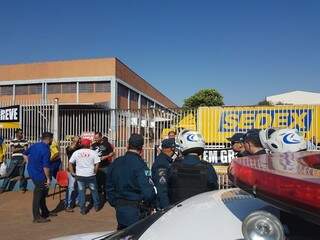 Sindicalistas e PM em frente ao portão trancado da central de distribuição (Foto: André Bittar)