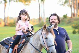 O pai ensinado a filha montar em cavalo (Foto: Estância Itália)