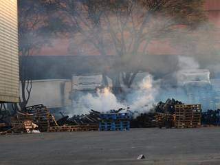 Paletes jogados no estacionamento ainda queimavam pela manhã; equipe da brigada de incêndio do supermercado trabalhava no resfriamento do material. (Foto: Henrique Kawaminami)