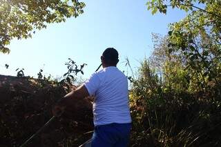 Voluntários se arriscam escalando barrancos para recolher lixo da margem. (Foto: Fernando Antunes)