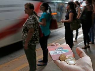 Usuário segura cartão e moedas em ponto de ônibus; imagem feita em 2015, quando a passagem ainda custava R$ 3,25 (Foto: Gerson Walber/Arquivo)