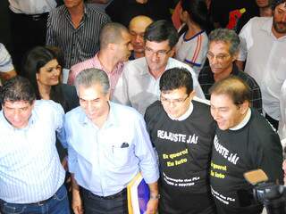 Reinaldo Azambuja prevê gastos de R$ 12 milhões. Bernal, de camiseta preta, estimou custo de R$ 7 milhões. 