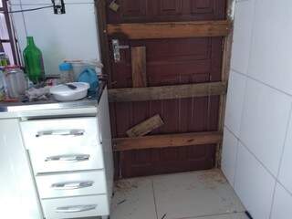 Enquanto a família providencia o conserto foi colocado madeira para não deixar a porta aberta  (Foto: Mirian Machado) 