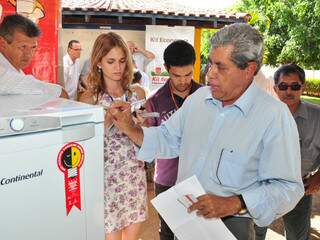 Após falar com repórteres, governador observa geladeira do programa de eficiência energética. (Foto: João Garrigó).