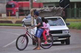 Morador com duas crianças na garupa de bicicleta para em frente a veículo durante bloqueio de rodovia (Foto: Eliel Oliveira)
