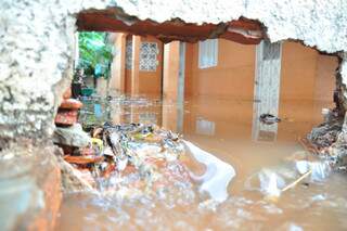 Muro precisou ser quebrado para escoamento da água em casa alagada na Vila Nhá Nhá. (Foto: João Garrigó)