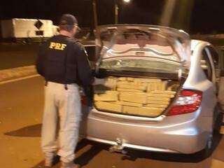 Policial observa tabletes de maconha no porta-malas de Honda Civic (Foto: Divulgação)