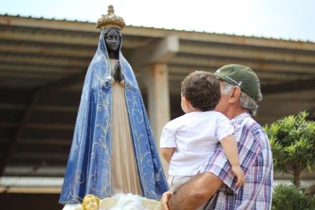 Avó com netinho contempla imagem de Nossa Senhora. (Foto: Marcos Ermínio)