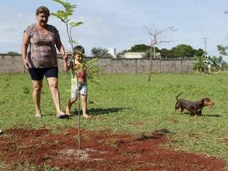 Professora Nazira ao lado do neto, de 5 anos, após plantar árvore em terreno do Bairro Vilas Boas. (Foto: Kísie Ainoã)