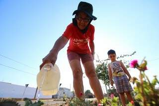 Na companhia do neto, dona Doracy joga água nas plantas todos os dias (Foto: André Bittar)