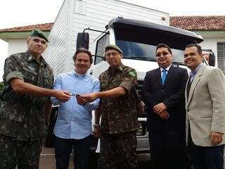 Marquinhos (no meio) recebe das mãos de militares as chaves dos furgões; na foto também os secretários de segurança Valério Azambuja (de terno) e de saúde Marcelo Vilela (às esquerda) (Foto: Kleber Clajus) 