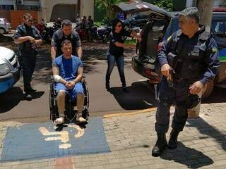 De cadeira de rodas, Camilo é conduzido por guardas municipais ao chegar ao Fórum de Dourados (Foto: Adilson Domingos)