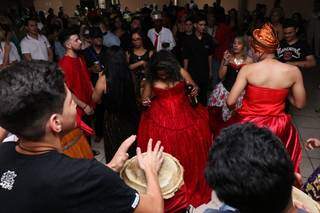 Enquanto ouvem a batucada, as Pombas-gira, vestidas de vermelho, dançam (Foto: Henrique Kawaminami)