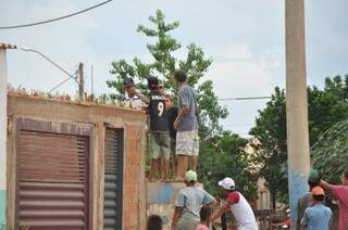 Meninos sobem em muro para invadir mercado na Cidade de Deus (Foto: Marcelo Calazans)