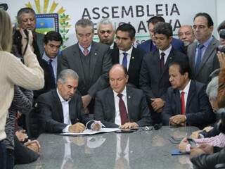 Reinaldo, à esquerda, assina o projeto de lei de redução do ICMS ao lado dos deputados. (Foto: Saul Schramm).