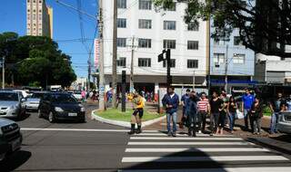 Agente de trânsito tenta organizar carros e pedestres no centro da cidade. 