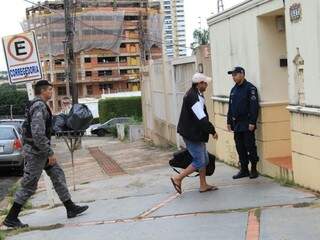 De boné e bermuda, homem, possivelmente um dos PMs alvos da operação, chega à sede da Corregedoria com mala na mão (Foto: Marina Pacheco)