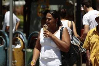 Mulher toma sorvete para afastar o calor.