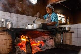 Cozinheira Dona Maria preparando o tradicional prato porco no tacho (Foto: Henrique Kawaminami)